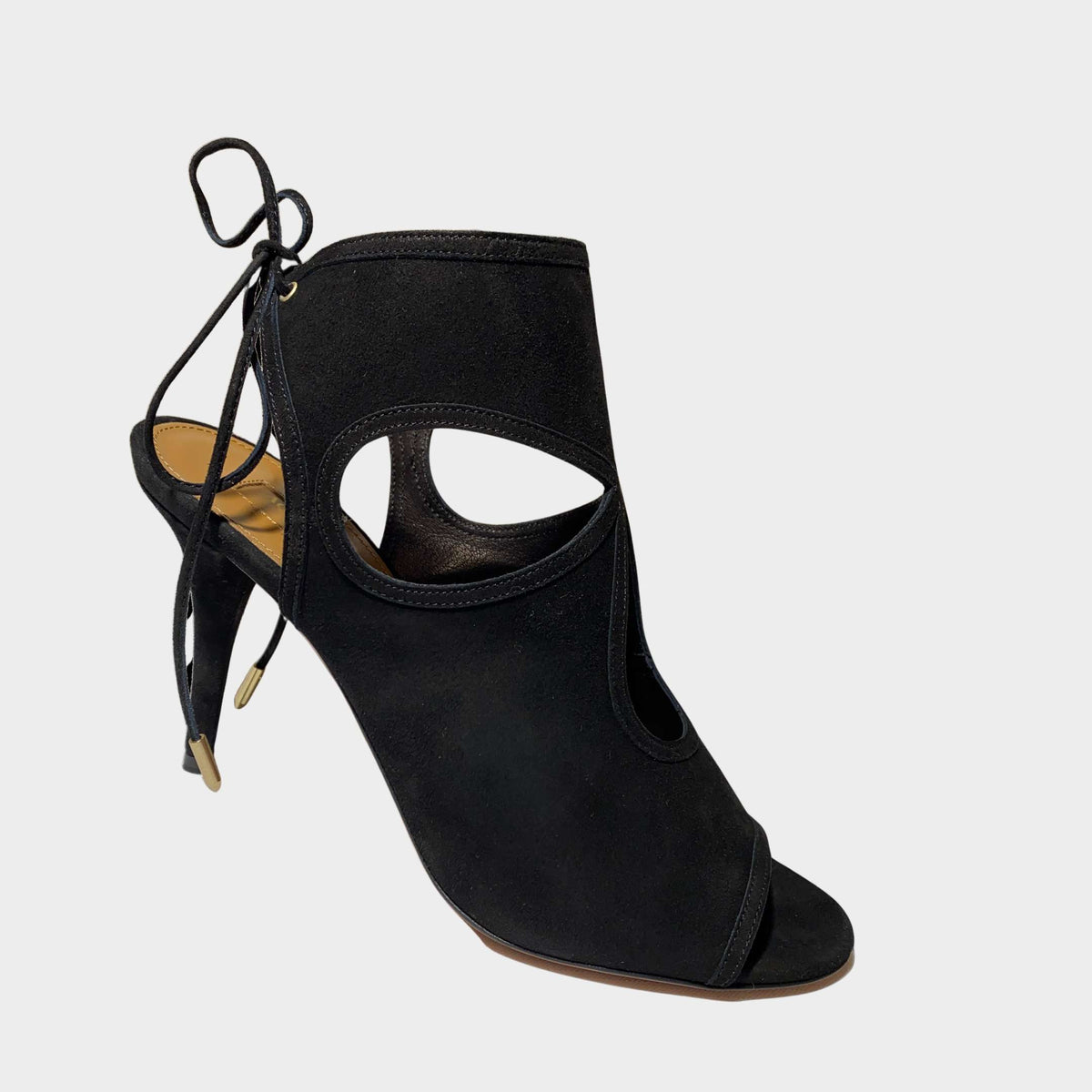 Side profile close-up of an Aquazzura Sexy Thing 85 sandal in black suede, showing the teardrop cut-outs and slim stiletto heel.