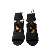 Front view of a pair of Aquazzura Sexy Thing 85 black suede sandals, showcasing the symmetrical open toe design and ankle tie styling.