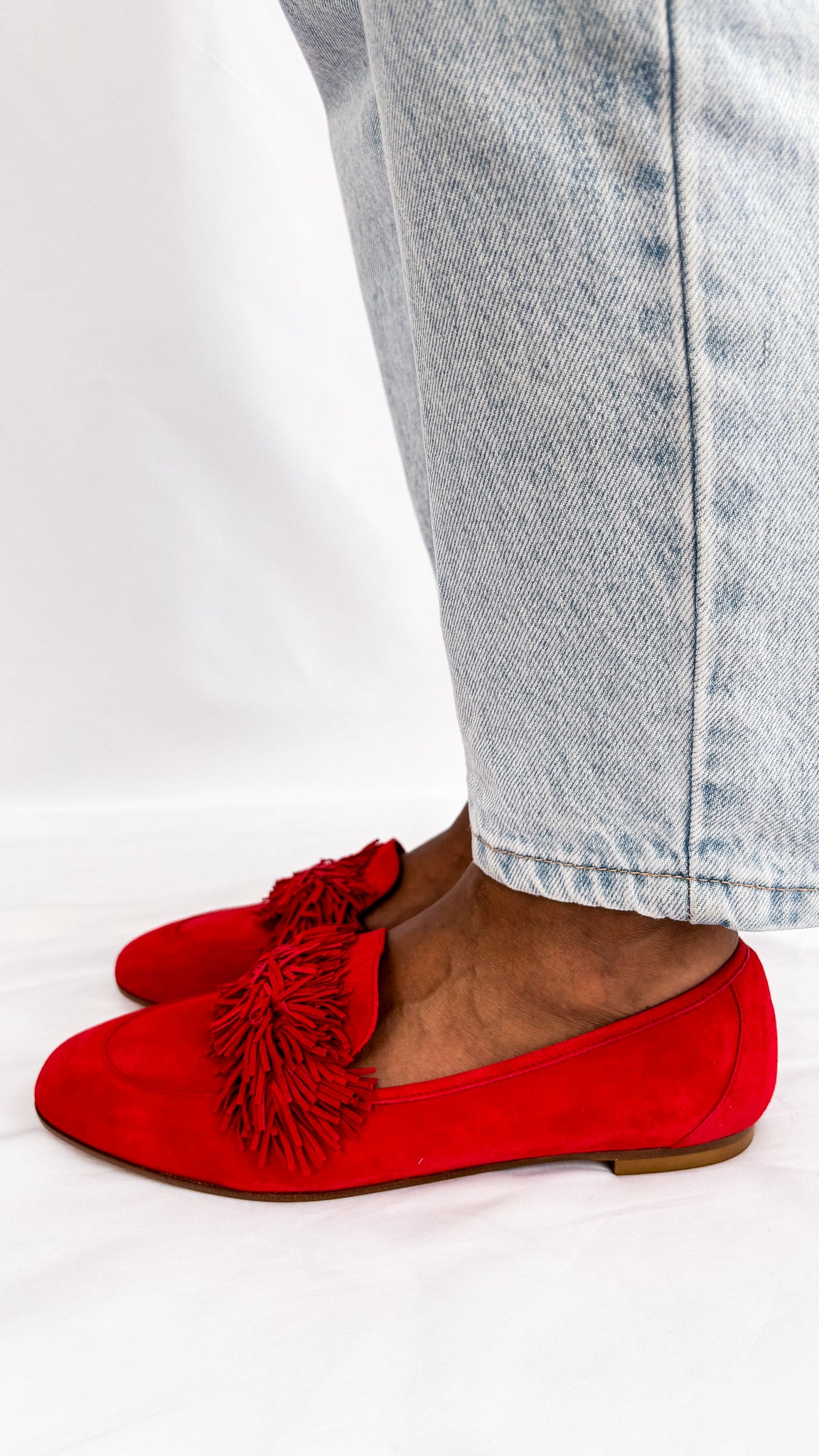 Side angle wearing shot of the Aquazzura Wild Thing red suede loafer flat, highlighting the low block heel and slip-on silhouette.