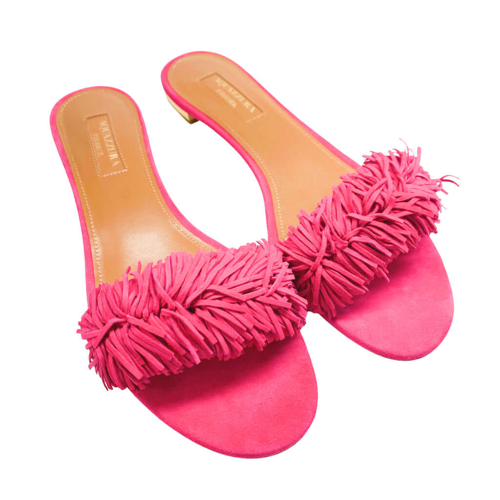 Front view of a pair of Aquazzura Wild Thing pink suede sandals, showcasing the vibrant color and dense fringe tassel detail across the toe strap.