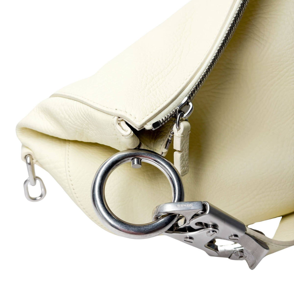 Close-up view of the silver-tone horse clip fastener and ring detailing on the lime yellow Burberry Knight bag.