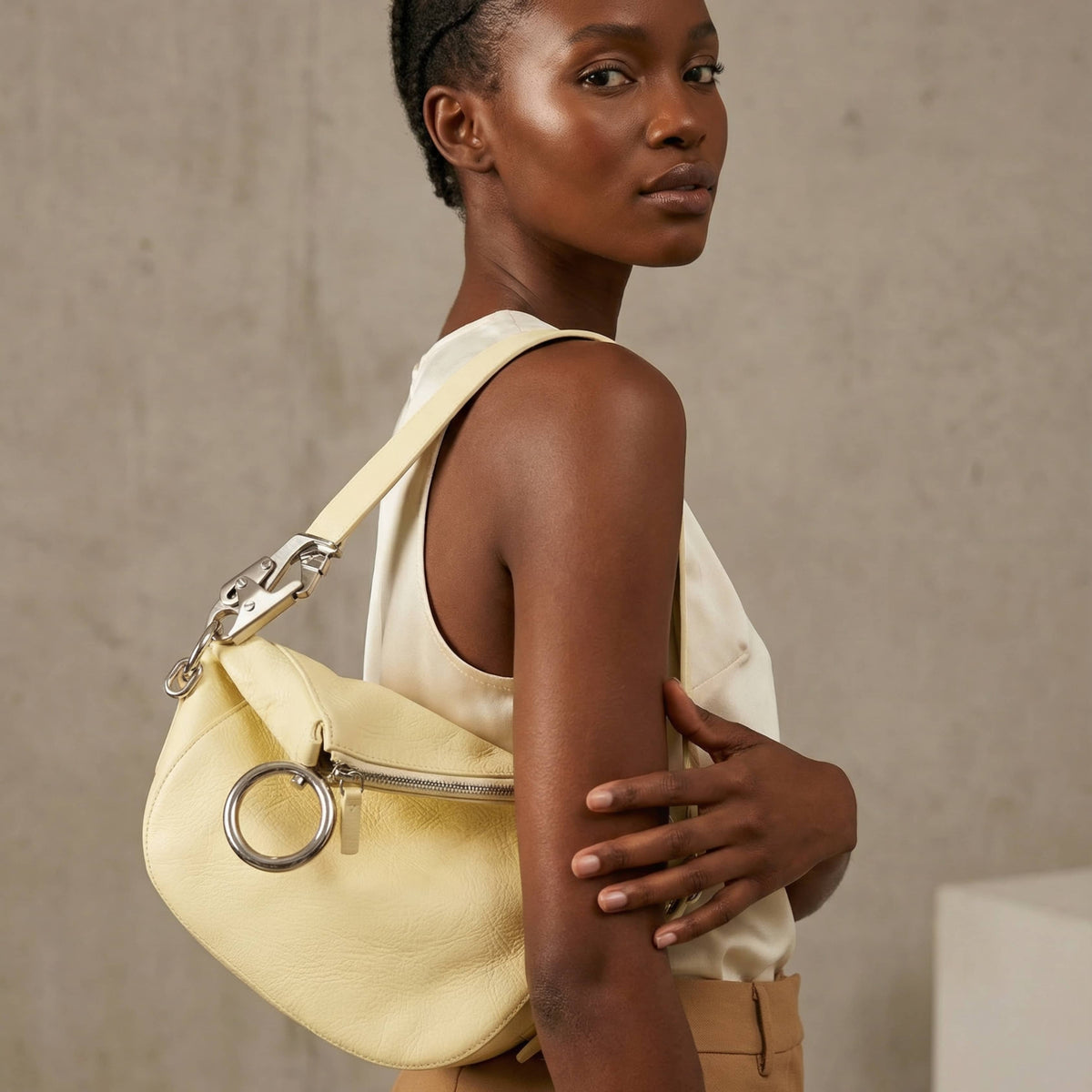 On-body side view of a model carrying the lime yellow Burberry Knight shoulder bag, showcasing its medium size and slouchy hang.