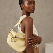 On-body side view of a model carrying the lime yellow Burberry Knight shoulder bag, showcasing its medium size and slouchy hang.