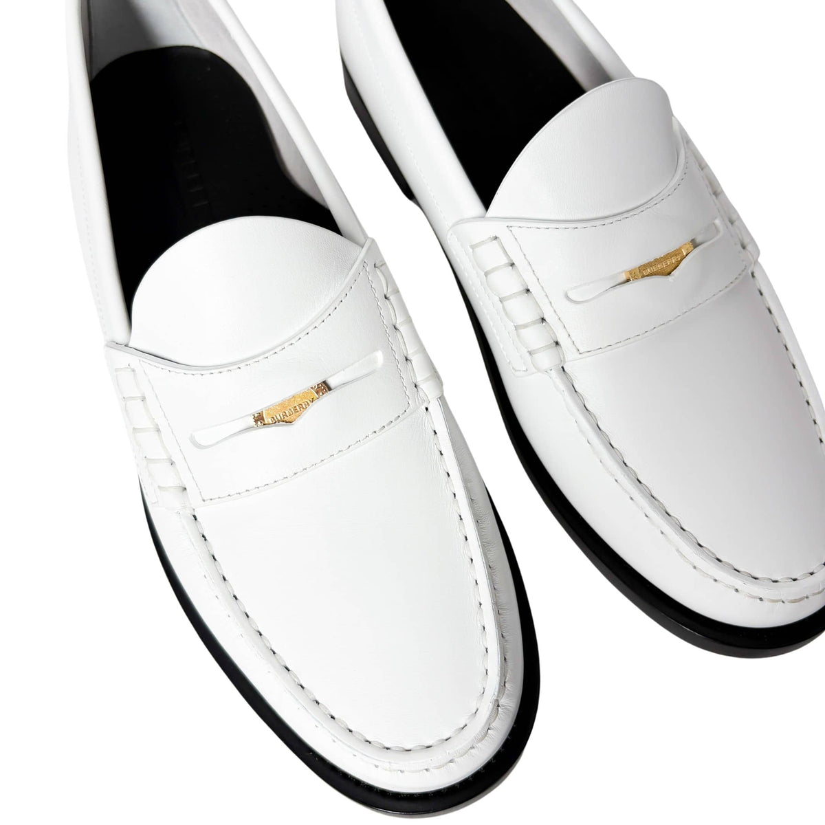 On-foot wearing view of the white leather Burberry Rupert Coin Loafers, showcasing a smart-casual styled look.