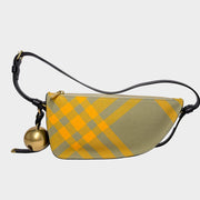 Front view of the Burberry Shield shoulder bag in yellow and grey canvas check, featuring a hanging gold bell charm.