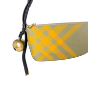 Side profile of the Burberry Shield canvas bag, highlighting its slim, asymmetrical shape and black leather shoulder strap.