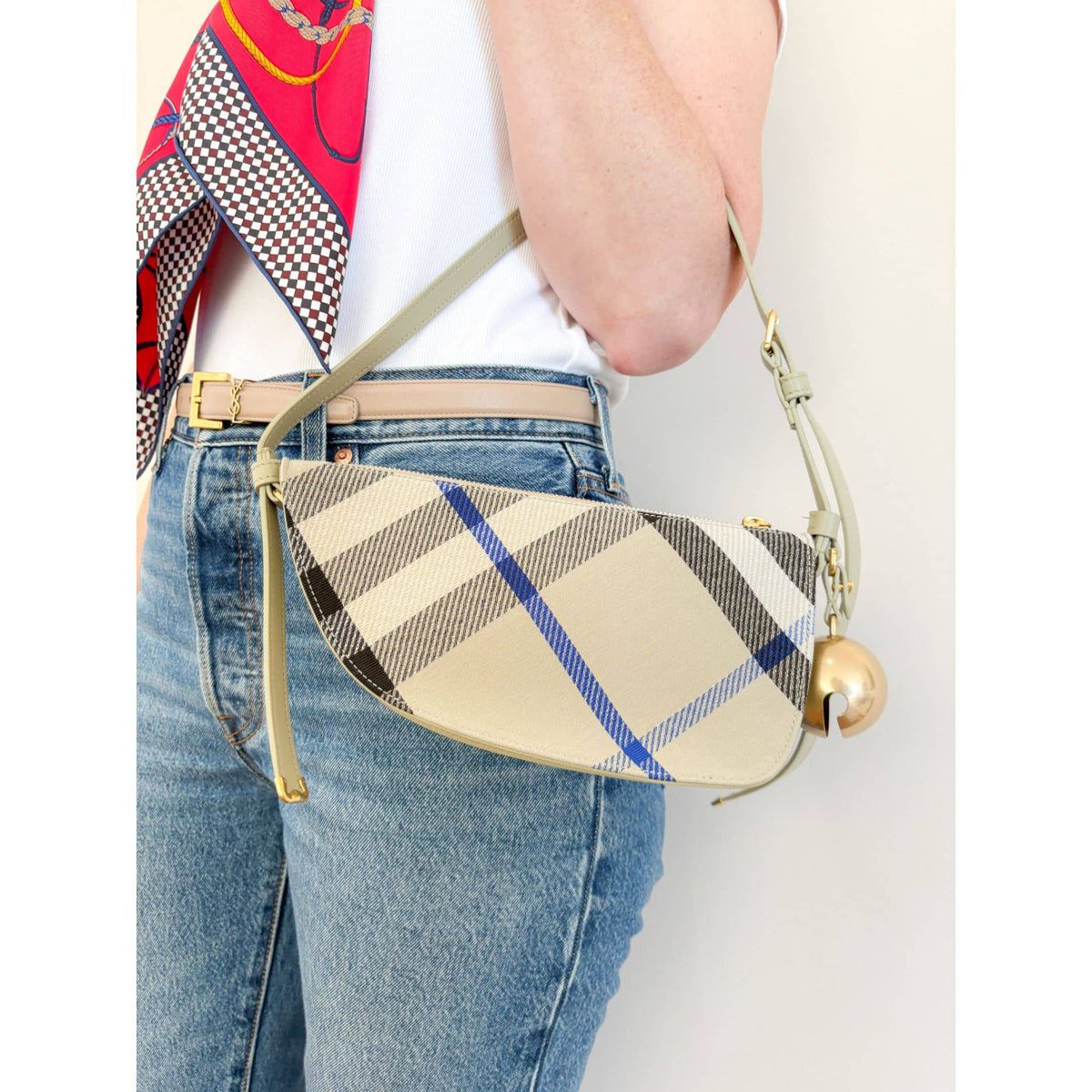 On-body view of a model carrying the blue and beige Burberry Shield canvas bag, demonstrating its medium size and casual fit.