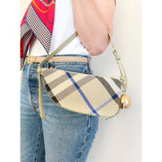 On-body view of a model carrying the blue and beige Burberry Shield canvas bag, demonstrating its medium size and casual fit.