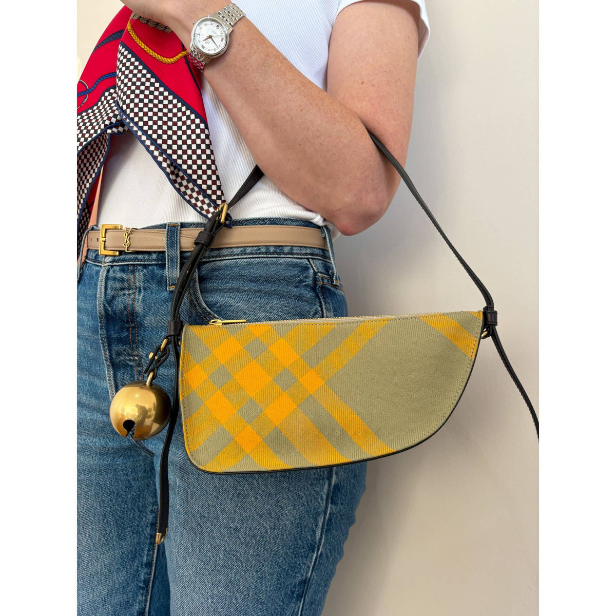 On-body view of a model wearing the yellow and grey Burberry Shield shoulder bag, showcasing its compact size and casual fit.