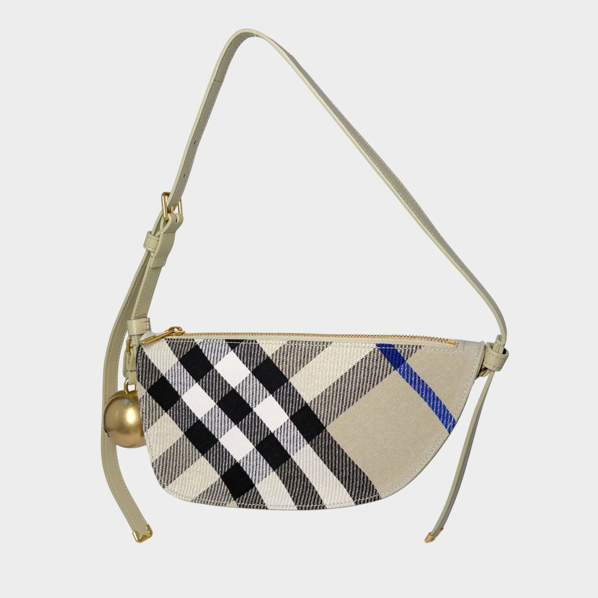 Front view of the Burberry Shield shoulder bag in classic beige, black, and blue Check canvas, featuring a hanging gold bell charm.