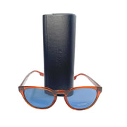 Front view of Burberry brown sunglasses with blue lenses displayed resting in front of their included black hard leather case.