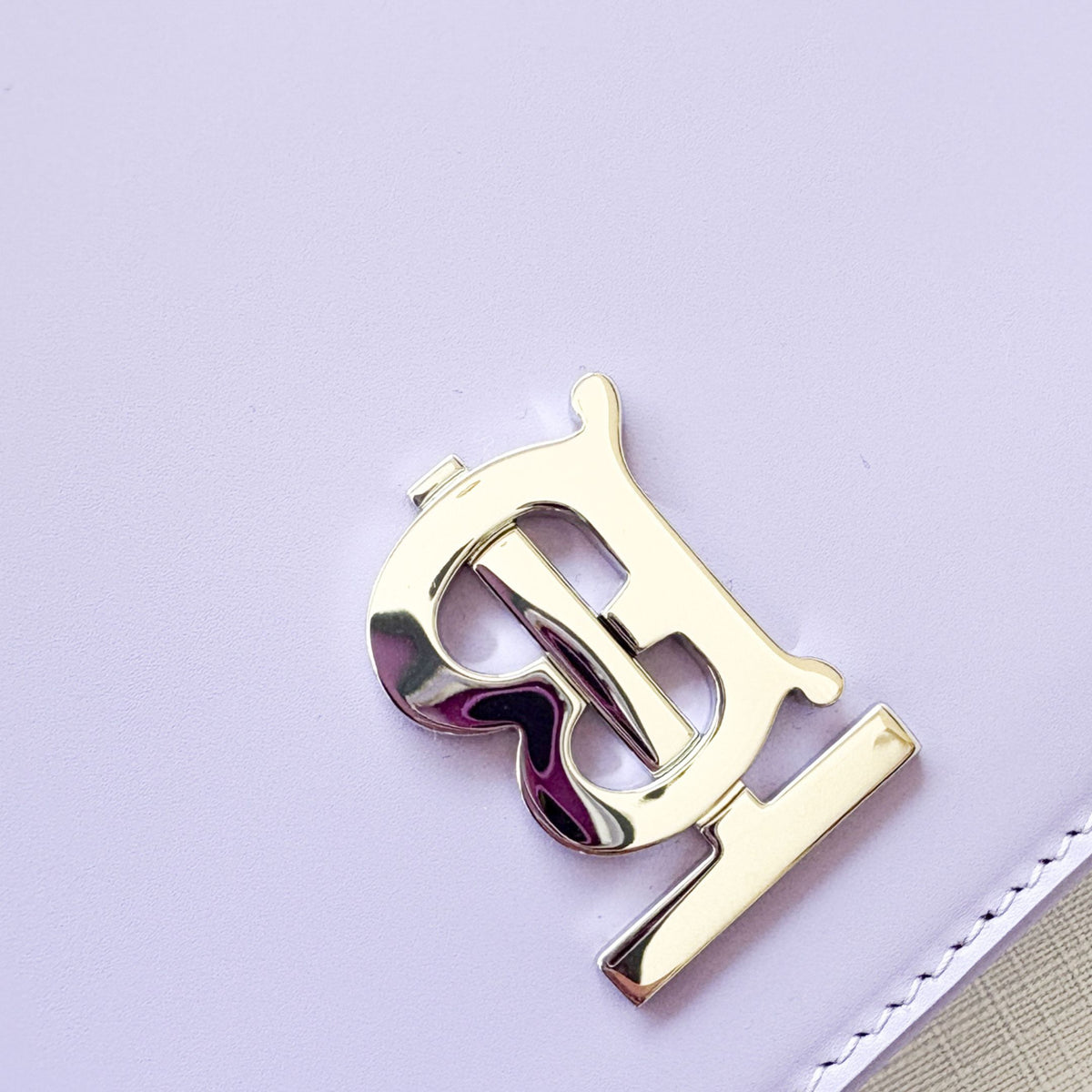 Close-up view of the iconic silver-tone Thomas Burberry (TB) monogram clasp on the lilac leather shoulder bag.