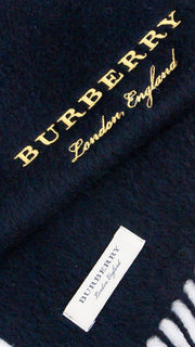 Angled close-up of black Burberry cashmere scarf showing yellow gold embroidered logo and white designer tag.