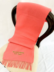 Burberry coral pink 100% cashmere scarf with fringe hem draped gracefully over a display stand.