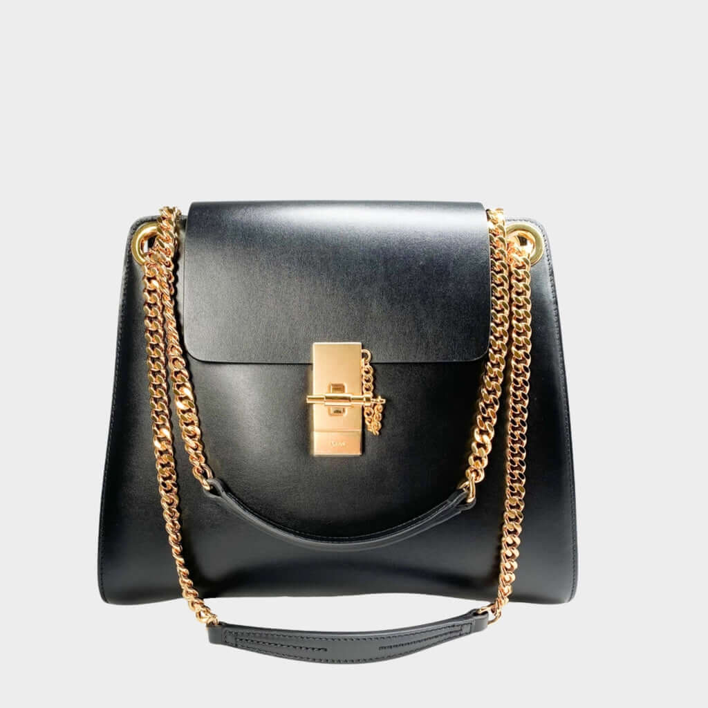 Front view of the classic black Chloé Annie bag in shiny calfskin leather, showcasing the iconic gold turn-lock and chain hardware.