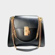 Front view of the classic black Chloé Annie bag in shiny calfskin leather, showcasing the iconic gold turn-lock and chain hardware.