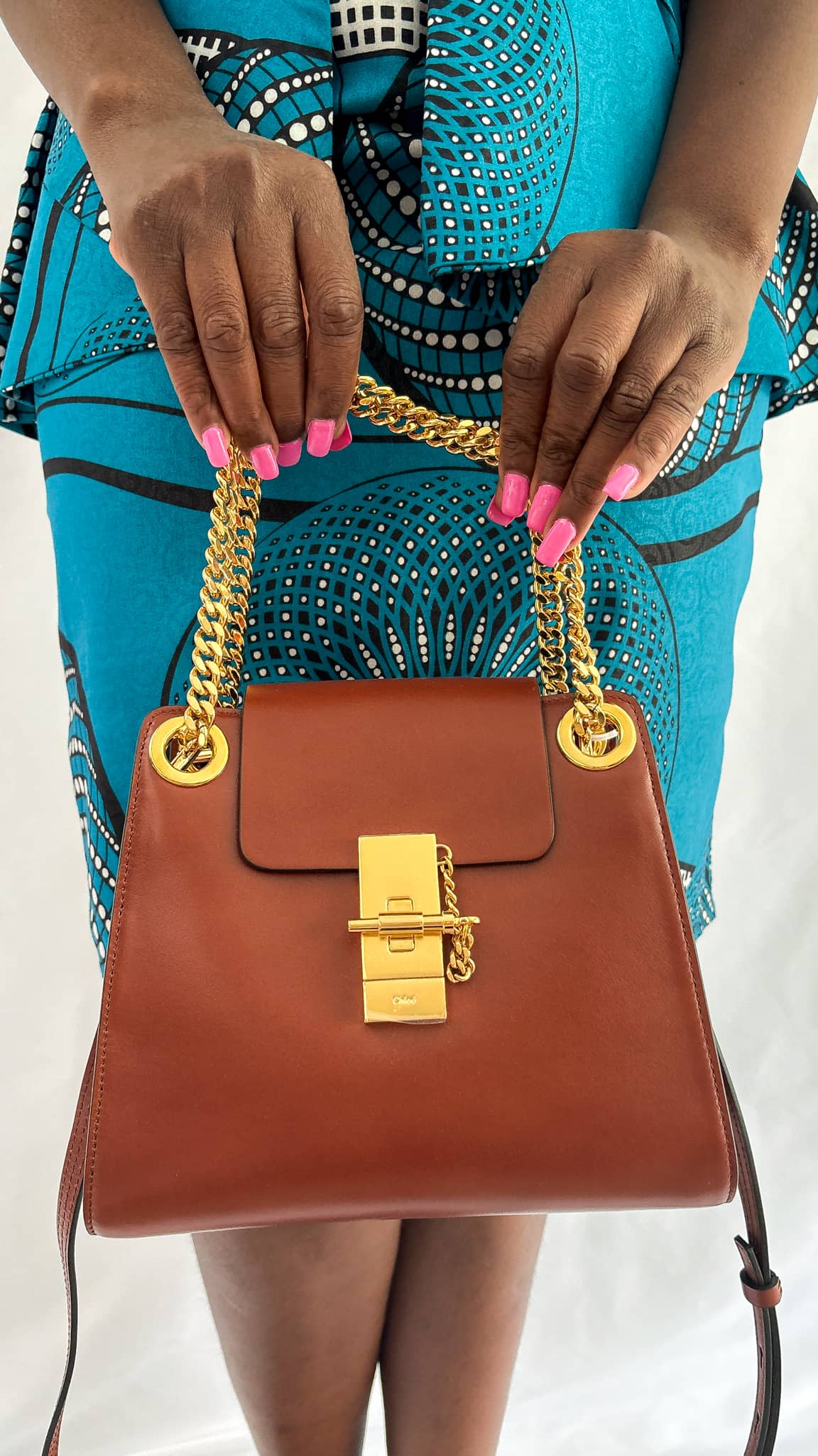 Close-up on-body view of the Chloé Annie brown leather handbag styled with a blue outfit, highlighting the short top carry handle.