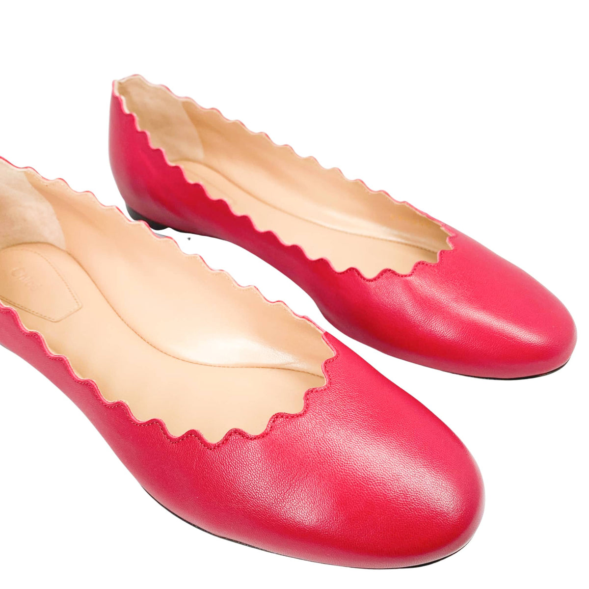 Front perspective view of a pair of Chloé Lauren pink leather ballet flats against a white background, showcasing the symmetrical scalloped edges.