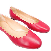 Front perspective view of a pair of Chloé Lauren pink leather ballet flats against a white background, showcasing the symmetrical scalloped edges.