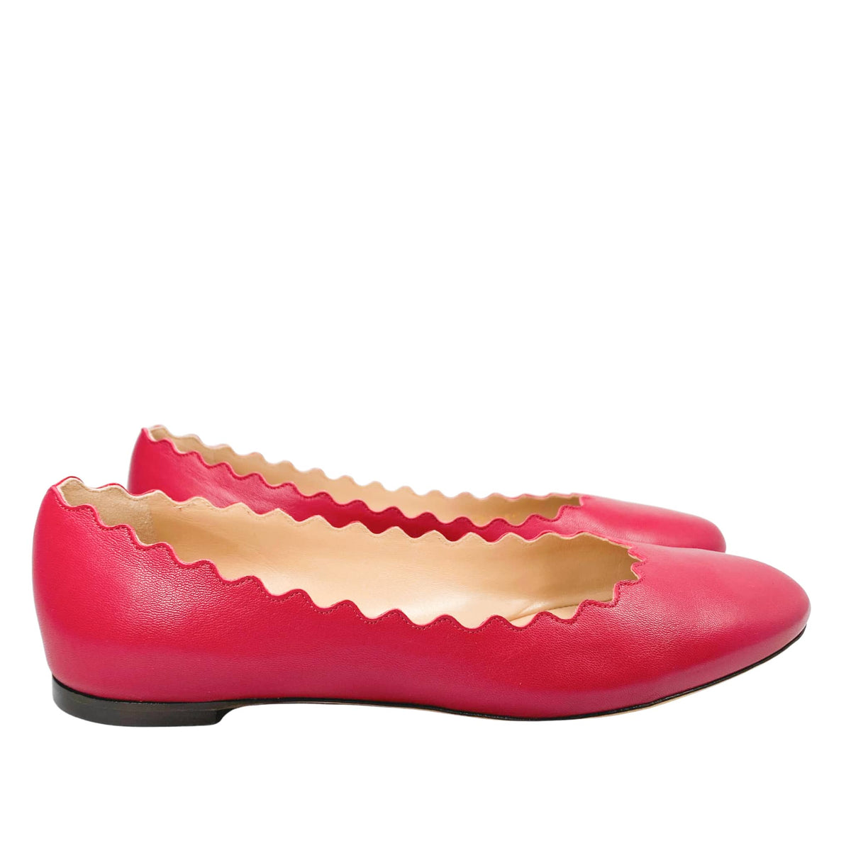 Side angle studio shot of a pair of Chloé Lauren scalloped ballet flats in raspberry sorbet pink leather.