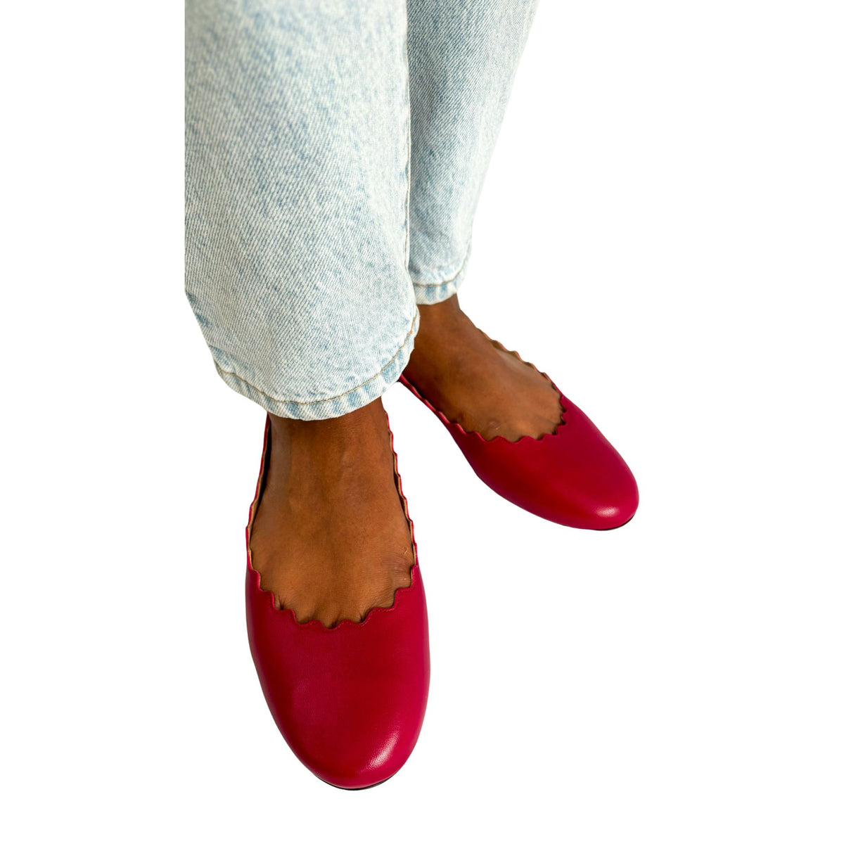 Top-down on-foot view of a pair of Chloé Lauren raspberry sorbet pink leather flats styled with light wash denim jeans.