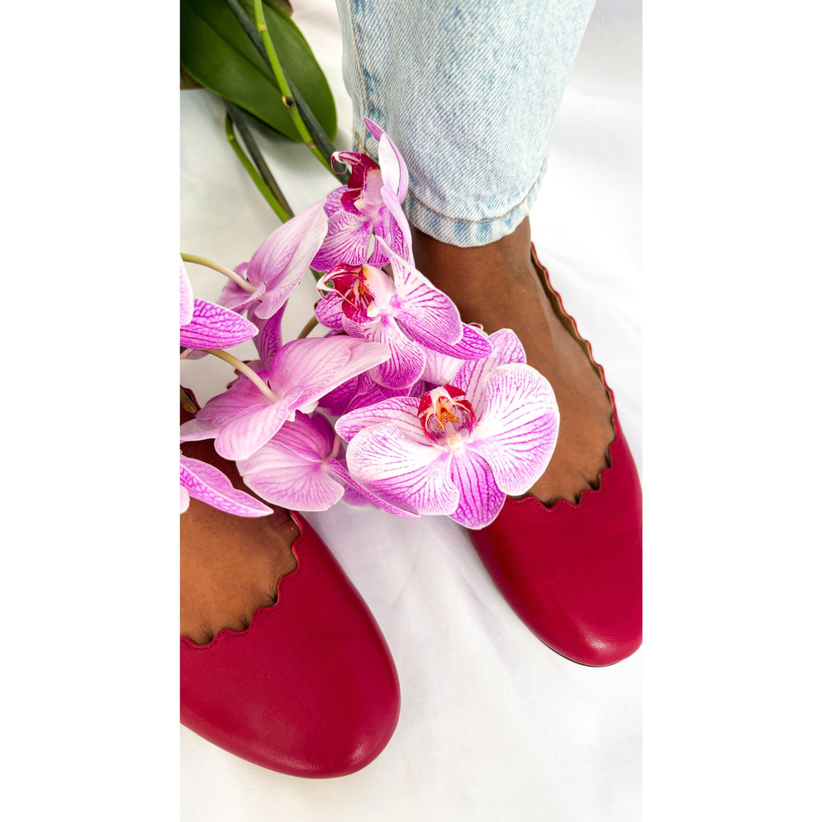 On-foot wearing view of Chloé Lauren raspberry sorbet ballet flats styled alongside a vibrant pink orchid bouquet.