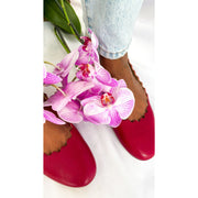 On-foot wearing view of Chloé Lauren raspberry sorbet ballet flats styled alongside a vibrant pink orchid bouquet.