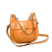 Front studio view of the Chloé Tess shoulder bag in tan leather against a white background, featuring its curved saddle shape and long crossbody strap.