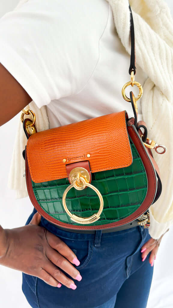 On-foot wearing view of a model carrying the multi-tone green and brown Chloé Tess bag crossbody, styled with a classic Gucci belt.