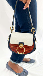 Side profile angle of the Chloé Tess shoulder bag showcasing its croc and lizard embossed leather textures and gold-tone side attachment.