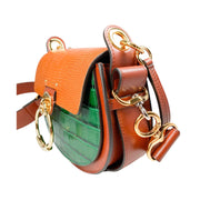 Right side three-quarter profile of the Chloé Tess bag, highlighting the mixed croc and lizard embossed textures, rounded saddle silhouette, and wide leather shoulder strap.