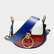 Front view of the Chloé Tess shoulder bag in blue, brown, and white colorblock leather, featuring its iconic gold-toned ring hardware.
