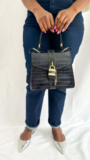Front perspective of a model holding the navy blue croc-embossed Chloé Aby Day shoulder bag, highlighting its structured upright silhouette.