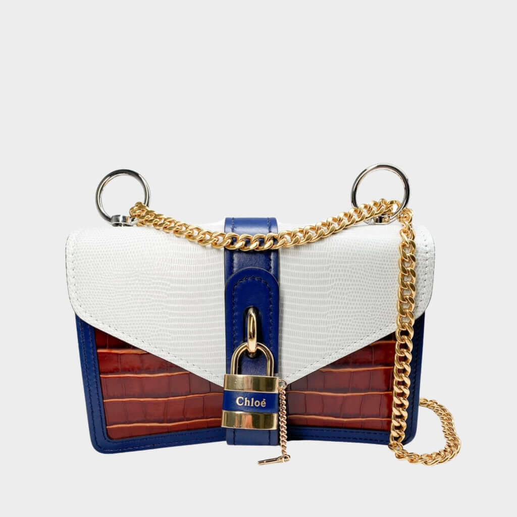 Front view of the Chloé Aby Day Chain bag in blue, brown, and white croc-effect leather, featuring its iconic gold-tone padlock.