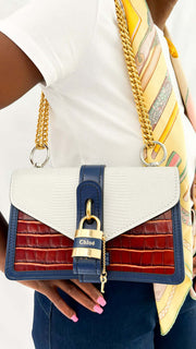 On-body side angle of a model wearing the Chloé Aby Chain bag, demonstrating the length of the gold-tone chain shoulder strap.