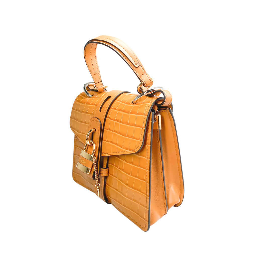 Right side three-quarter profile of the Chloé Aby Day brown leather bag, highlighting its softened structural angles and embossed texture details.