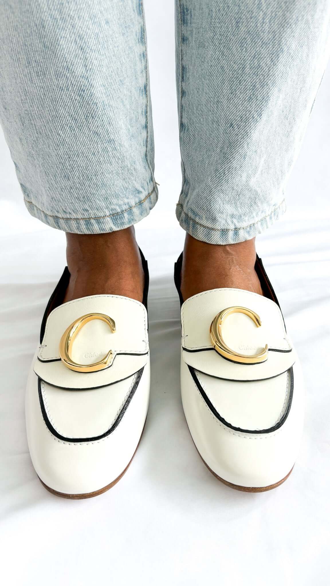 Front perspective wearing shot of the white Chloé C patent leather loafer flats, focusing on the golden C hardware accent.