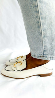 Side angle on-foot view of the Chloé C white patent leather loafers, showing the classic slip-on flat silhouette.