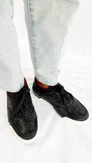 On-foot wearing view of the black Christian Louboutin Aurelien sneakers, paired with light wash denim jeans.