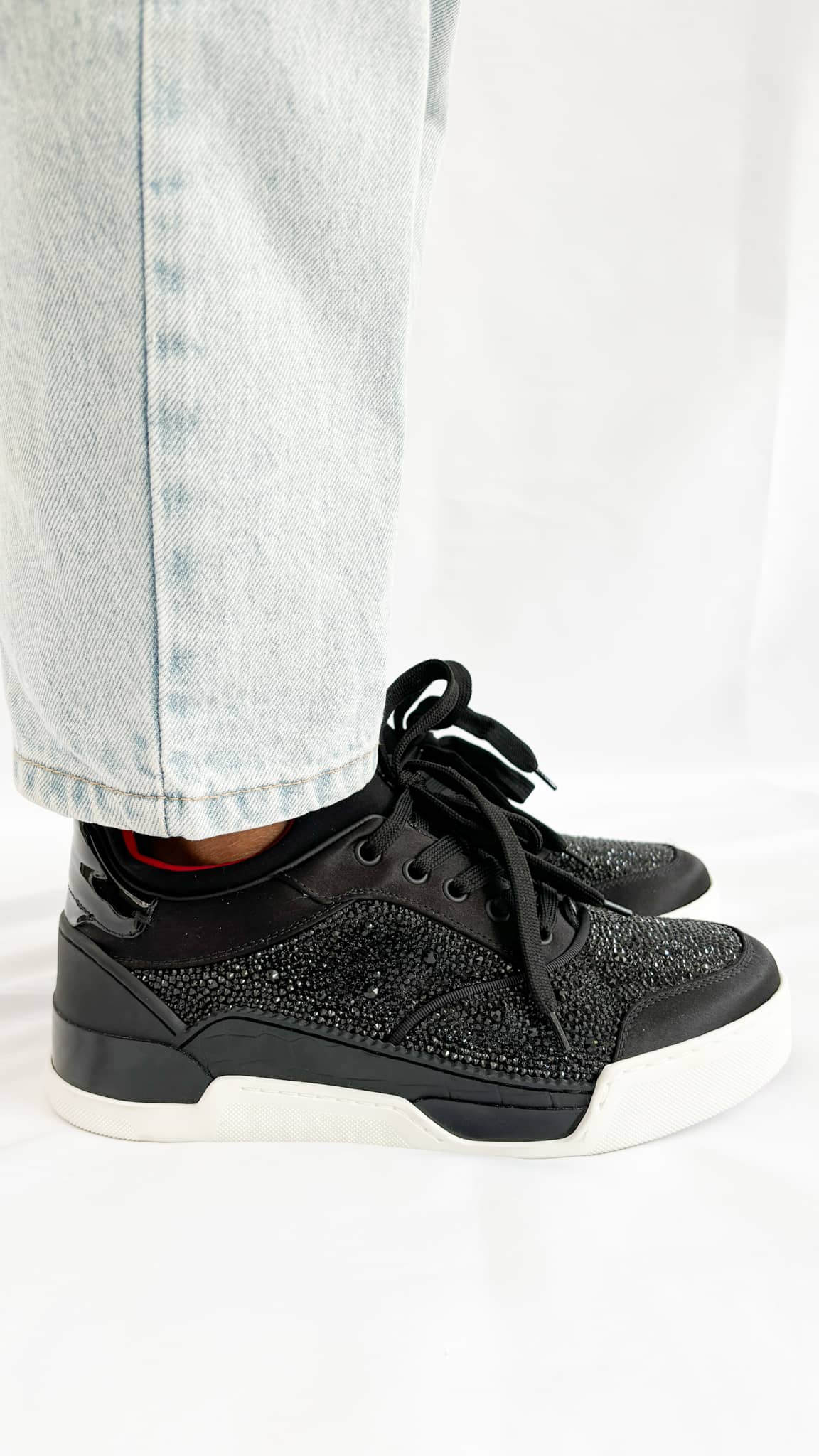 Side-angle view of the Christian Louboutin Aurelien trainer on-foot, highlighting the low-top silhouette and the clean white textured midsole line.