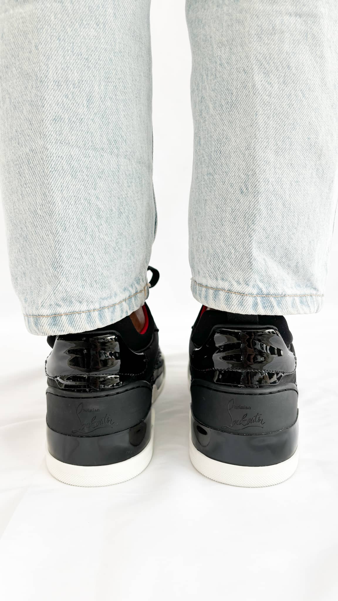 Rear view of the black Christian Louboutin Aurelien sneakers from behind on-foot, showcasing the padded heel counter and structured collar.