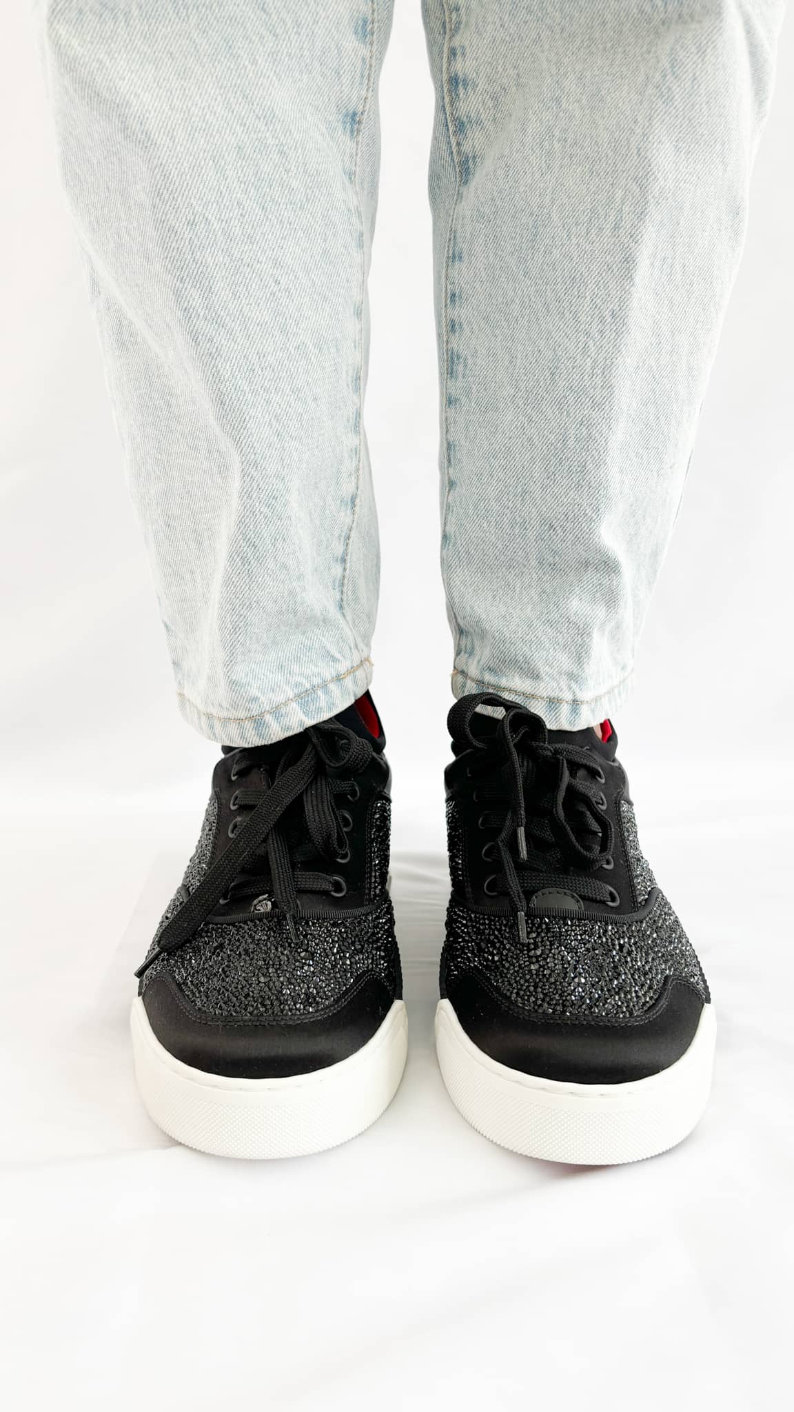 Front-facing view of the Christian Louboutin Aurelien black sneakers on-foot, showing the round toe and lace-up closure detail