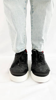 Front-facing view of the Christian Louboutin Aurelien black sneakers on-foot, showing the round toe and lace-up closure detail