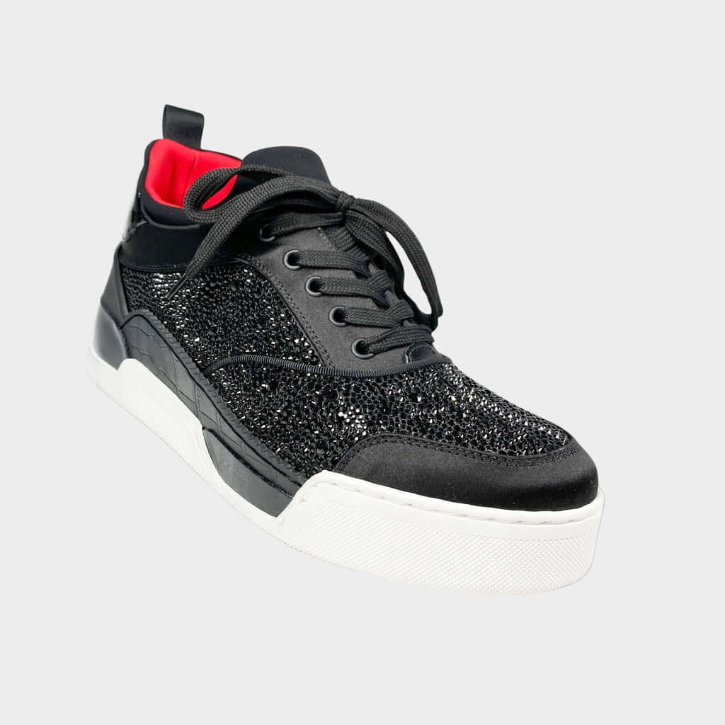 Side profile view of a Christian Louboutin Aurelien low-top sneaker in black leather and satin, featuring a glittery strass-embellished side panel and a chunky white rubber midsole.
