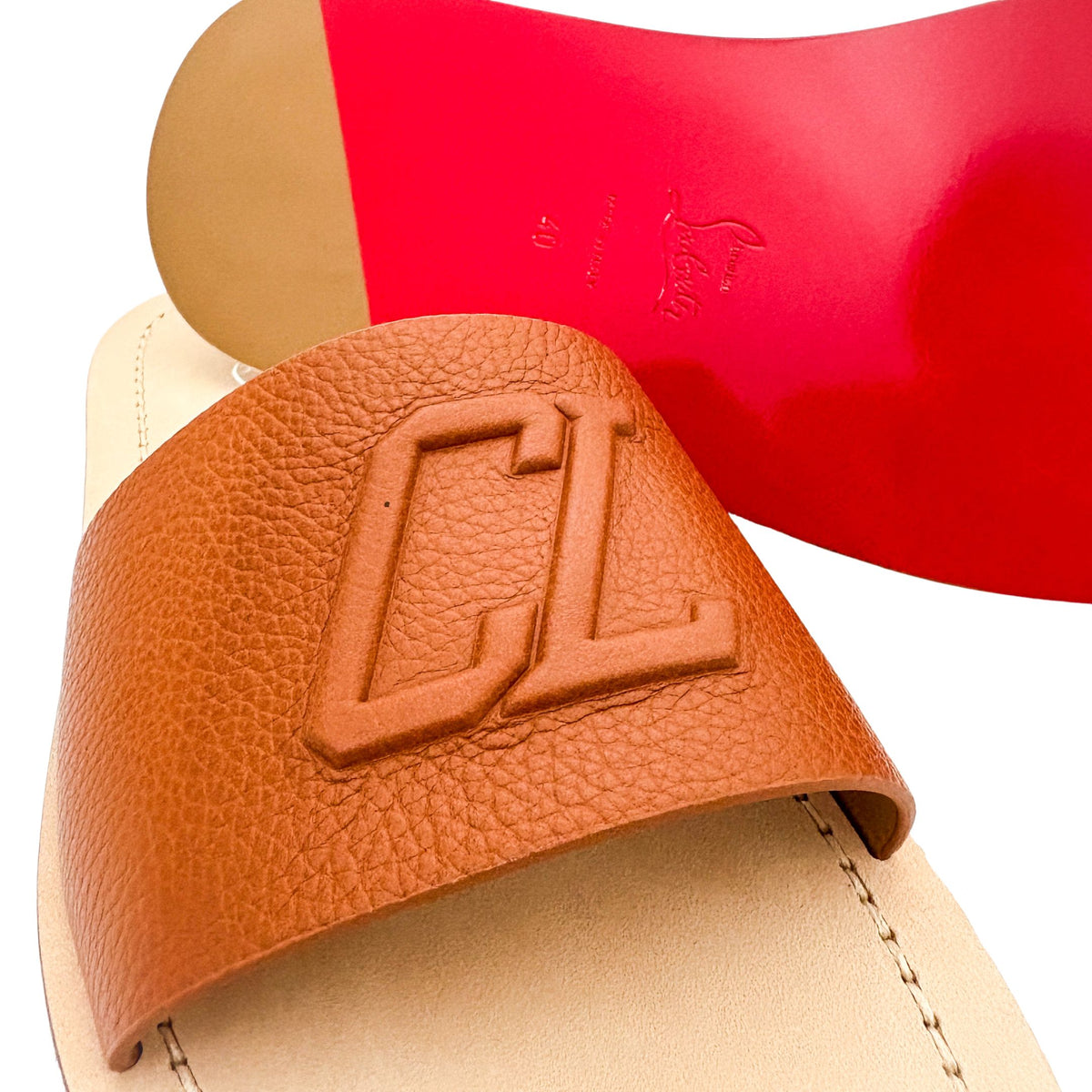 Close-up shot of a Christian Louboutin Varsicool slide tilted forward to showcase the iconic signature bright red rubber outsole.
