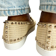 Rear three-quarter on-foot view of a model wearing the pink woven Christian Louboutin espadrille flats, highlighting the spiked trim.