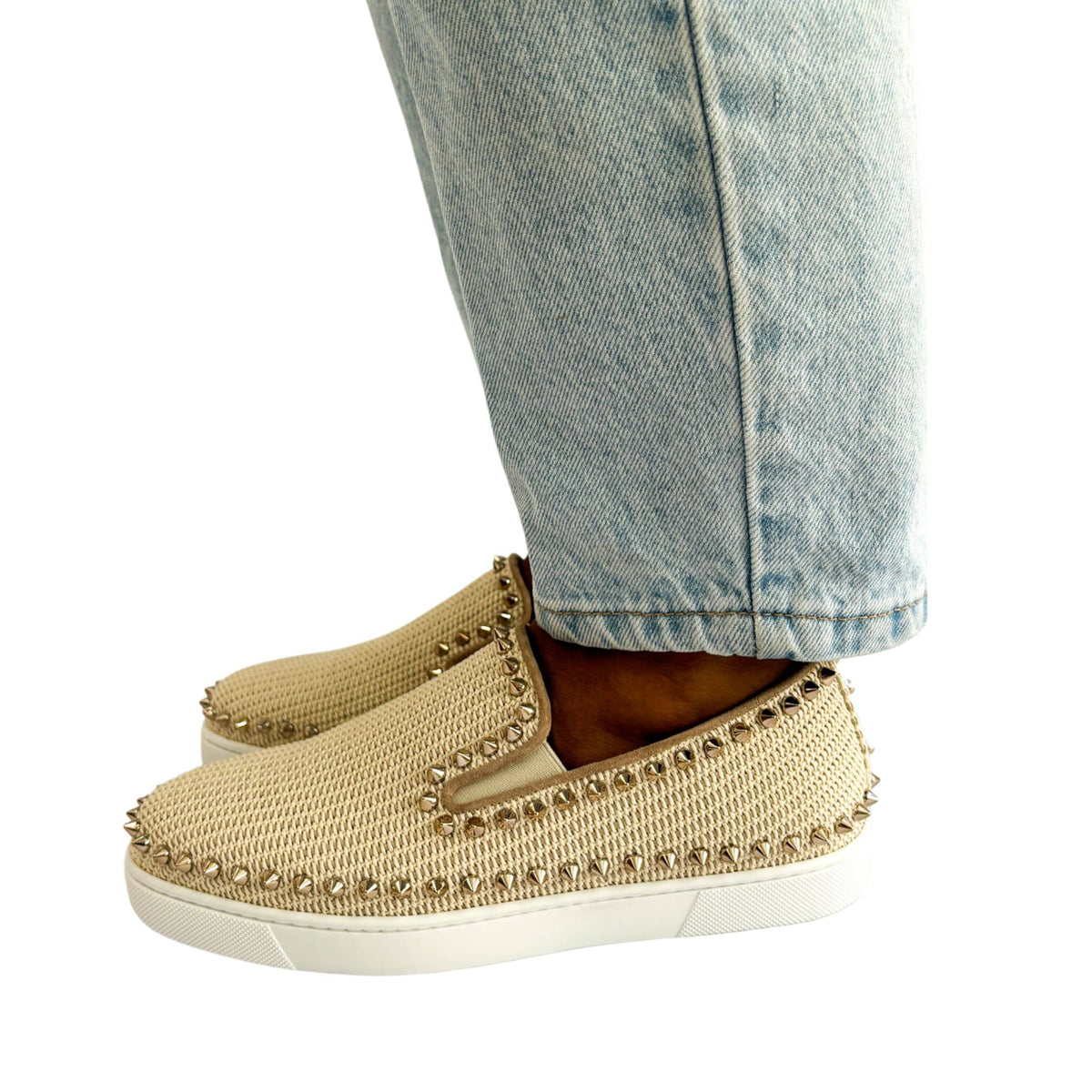 Side profile wearing view of the Christian Louboutin pink woven espadrilles with gold studs, showing the comfortable flat sole profile.