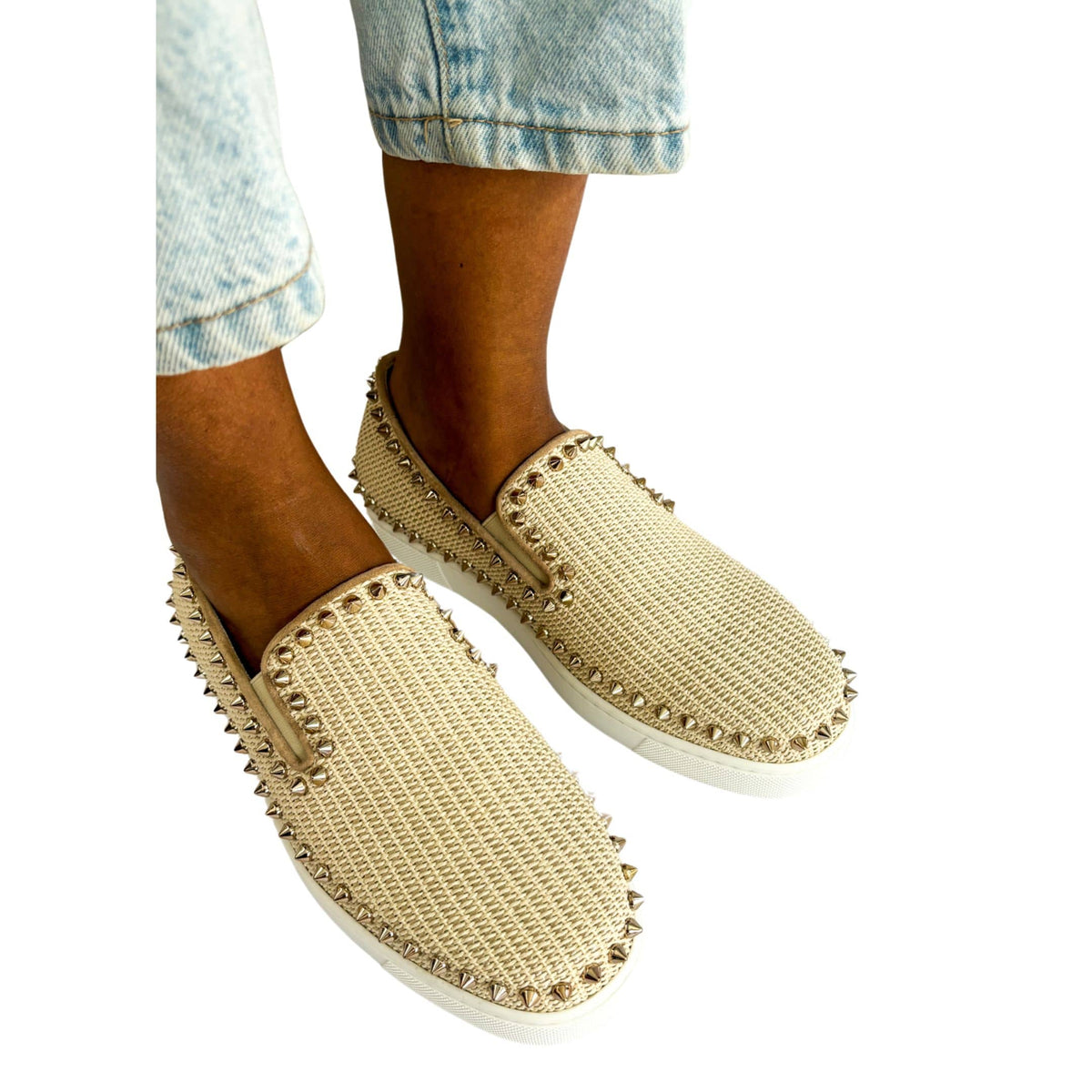 Top-down on-foot wearing view of a model in pink woven Christian Louboutin slip-on espadrilles styled with light wash blue jeans.