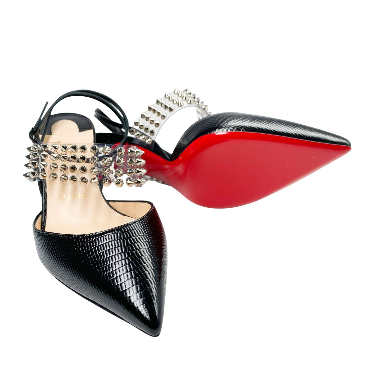 Studio shot of a pair of Christian Louboutin Levita 55 black leather and PVC heels positioned together, showcasing the signature red bottom soles.