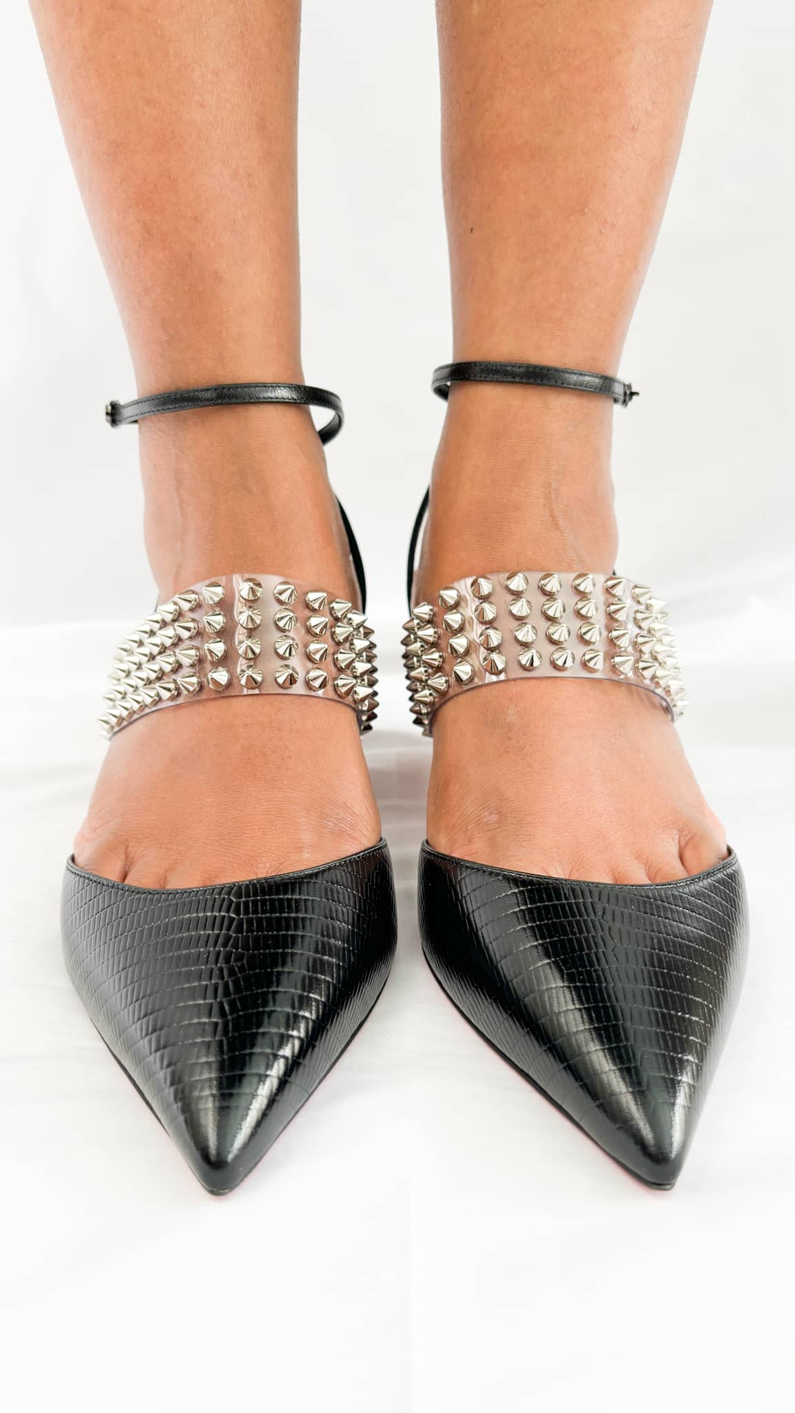 Symmetrical front perspective shot of a model wearing the black leather and clear PVC Christian Louboutin Levita 55 heels.